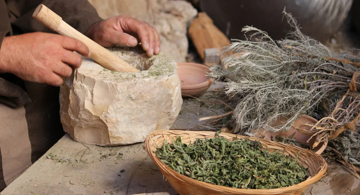 A person prepping dried herbs in a vintage Mortar and Pestle.